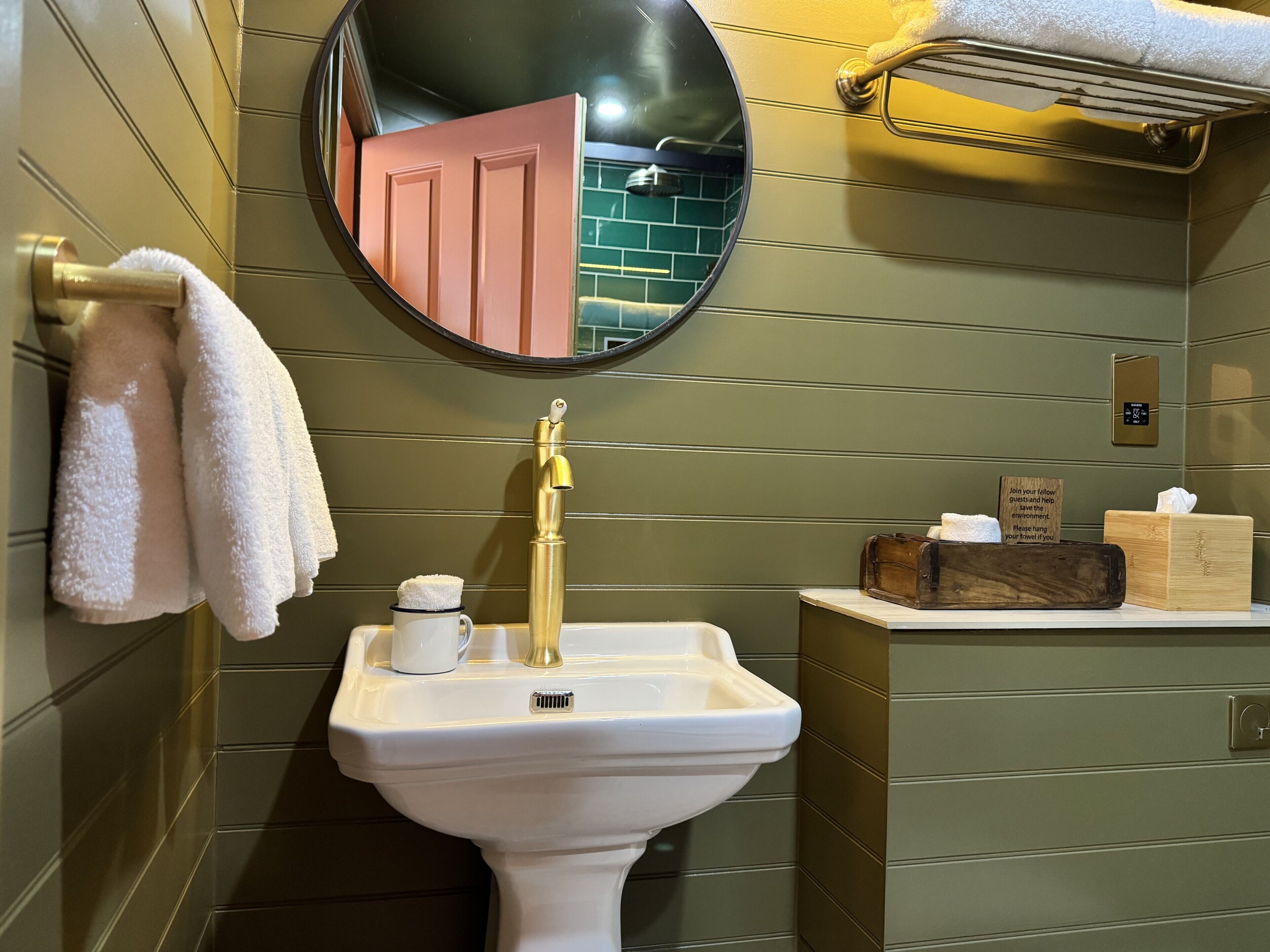 Une salle de bain équipée d’un lavabo, d’un miroir, d’un porte-serviettes et d’une pancarte.