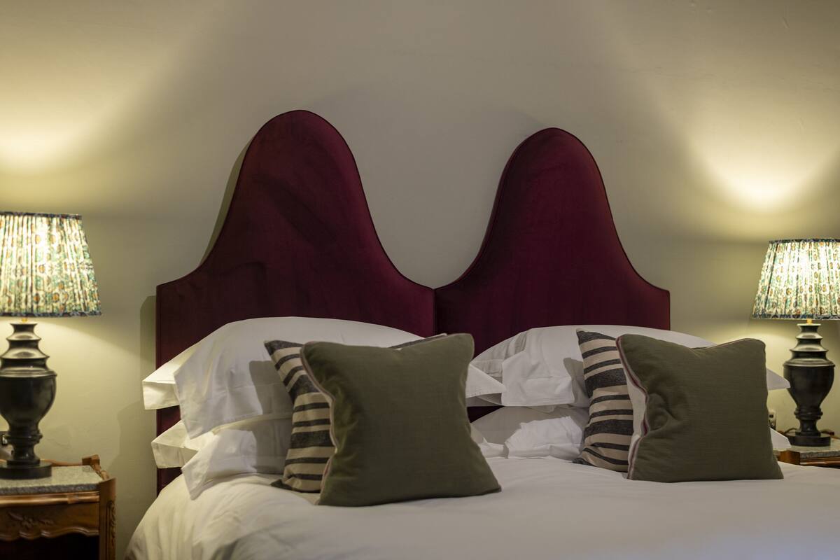 A hotel room with a large bed, two nightstands with lamps, and a headboard with a unique design.