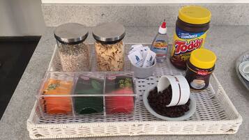 A kitchen counter with various food items and condiments, including jars of spices, a container of coffee beans, and a bottle of sauce.