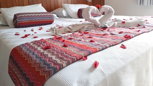 A hotel room with a wooden headboard, white bedding, and a decorative pillow. - Hotel Riviera Lins (Lins)
