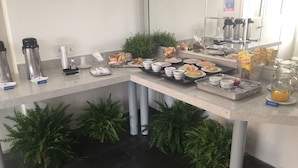 A buffet setup with various food items and beverages, including fruits, pastries, and a coffee station. - Hotel Riviera Lins (Lins)