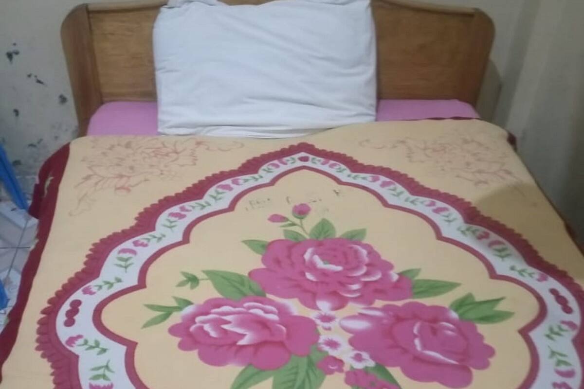Uma cama com colcha florida e travesseiro branco.