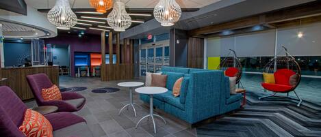 A modern lounge area with seating, tables, and hanging chairs.