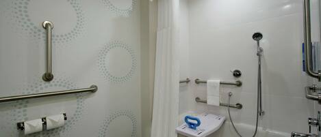 Een badkamer met douche, handgrepen, toilet en een handrail.