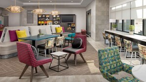 A modern living room with a sofa, chairs, a dining table, and a TV. - Home2 Suites by Hilton Denver Central Park (Denver)