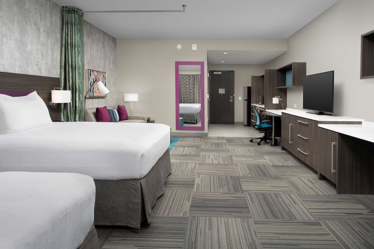 Camera d'albergo con un letto grande, una scrivania, una televisione e un bagno visibile attraverso una porta.