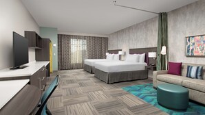A modern hotel room with a large bed, a sofa, a desk, and a TV. - Home2 Suites by Hilton Denver Central Park (Denver)
