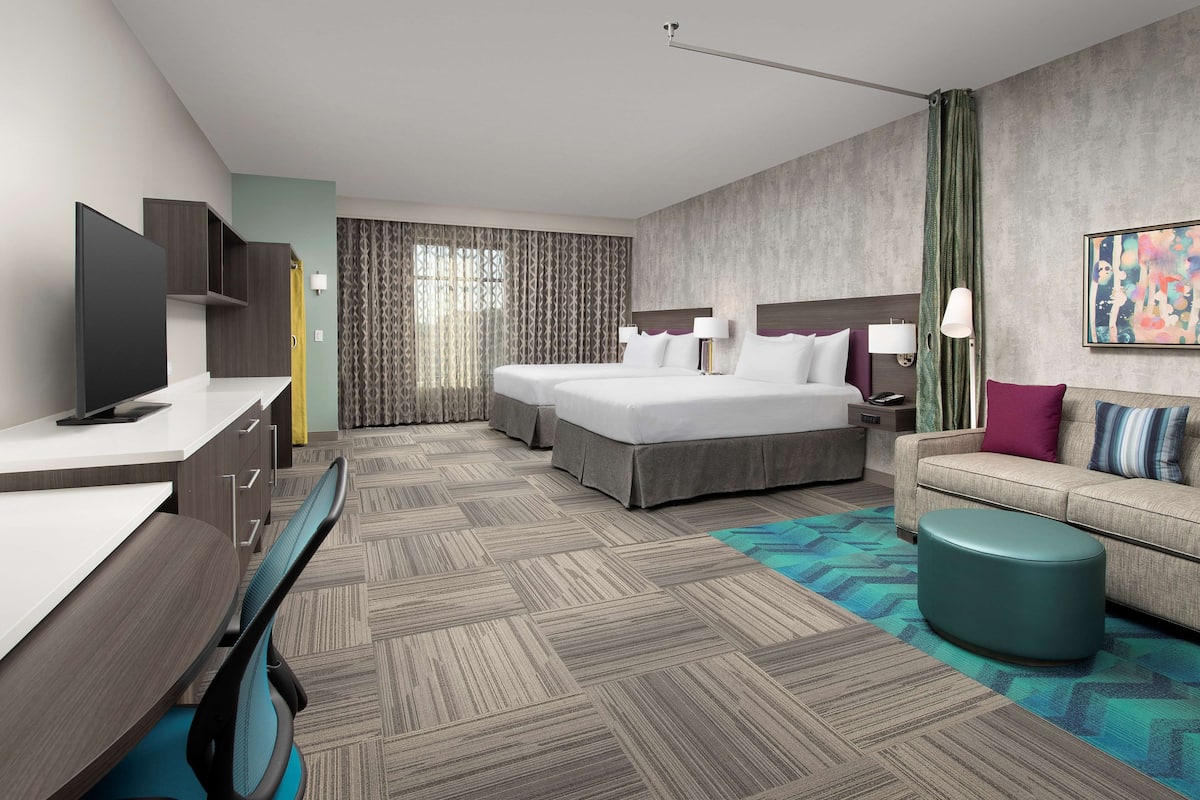 Una moderna camera d'hotel con un ampio letto, una poltrona, una scrivania e una TV.