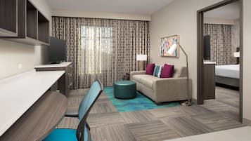 A hotel room with a desk, chair, sofa, and a bed.