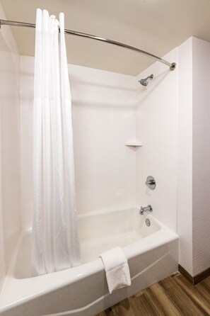 A modern bathroom with a bathtub, shower curtain, and a towel on the tub.