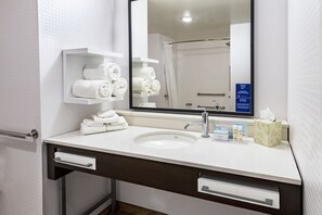 A bathroom with a white sink, a mirror, a towel rack, and a hand sanitizer dispenser.