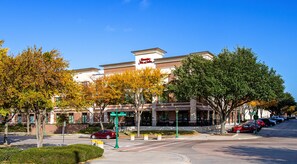A hotel with a brick facade, a sign reading 'Holiday Inn Express,' and a parking lot with cars.