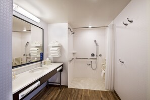 A modern bathroom with a large mirror, white sink, and a walk-in shower.