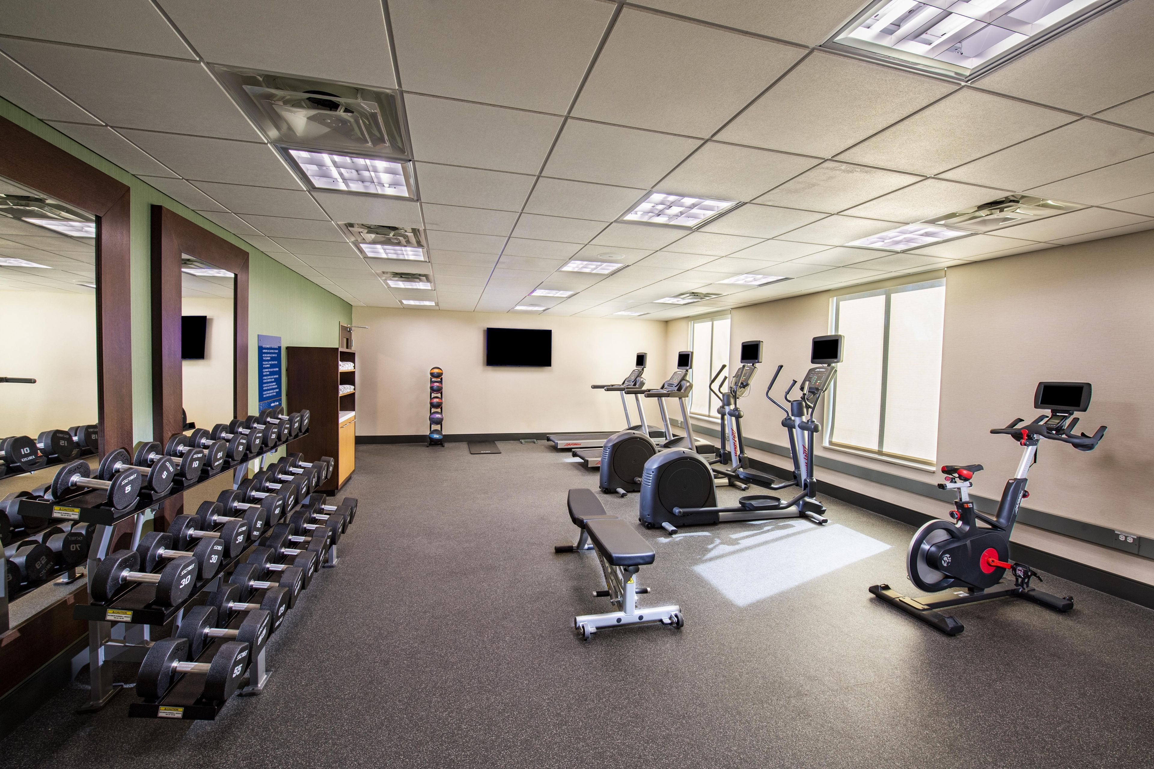 A gym with various exercise equipment, including dumbbells, treadmills, and stationary bikes.