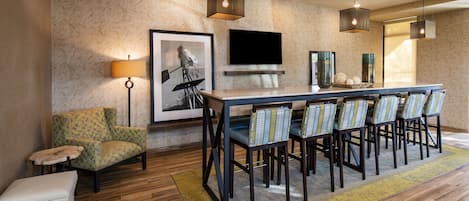 A modern dining area with a long table, chairs, and a television mounted on the wall.