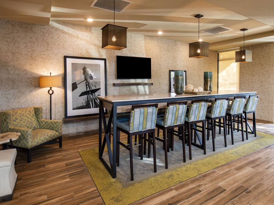 A modern dining area with a long table, chairs, and a television mounted on the wall.