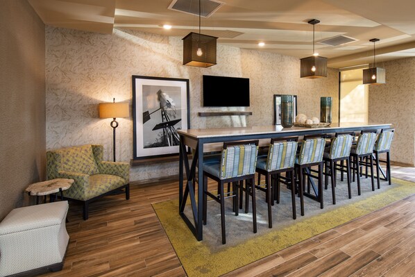 A modern dining area with a long table, chairs, and a television mounted on the wall.