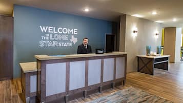 A reception desk with a 'WELCOME TO THE LONE STAR STATE' sign, a 'Hilton Honors' plaque, and a modern interior design.
