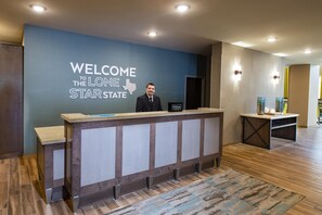 A reception desk with a 'WELCOME TO THE LONE STAR STATE' sign, a 'Hilton Honors' plaque, and a modern interior design.