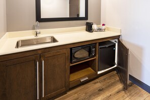 A compact kitchenette with a stainless steel sink, a microwave, and a coffee maker.
