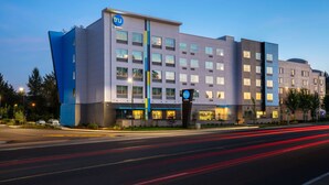 A modern hotel with a prominent 'TRU by Hilton' sign, multiple floors, and a well-lit facade. - Tru By Hilton Eugene, OR (Eugene)