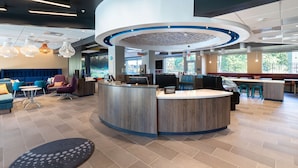 A modern hotel lobby with a central reception desk, seating area, and large windows. - Tru By Hilton Eugene, OR (Eugene)