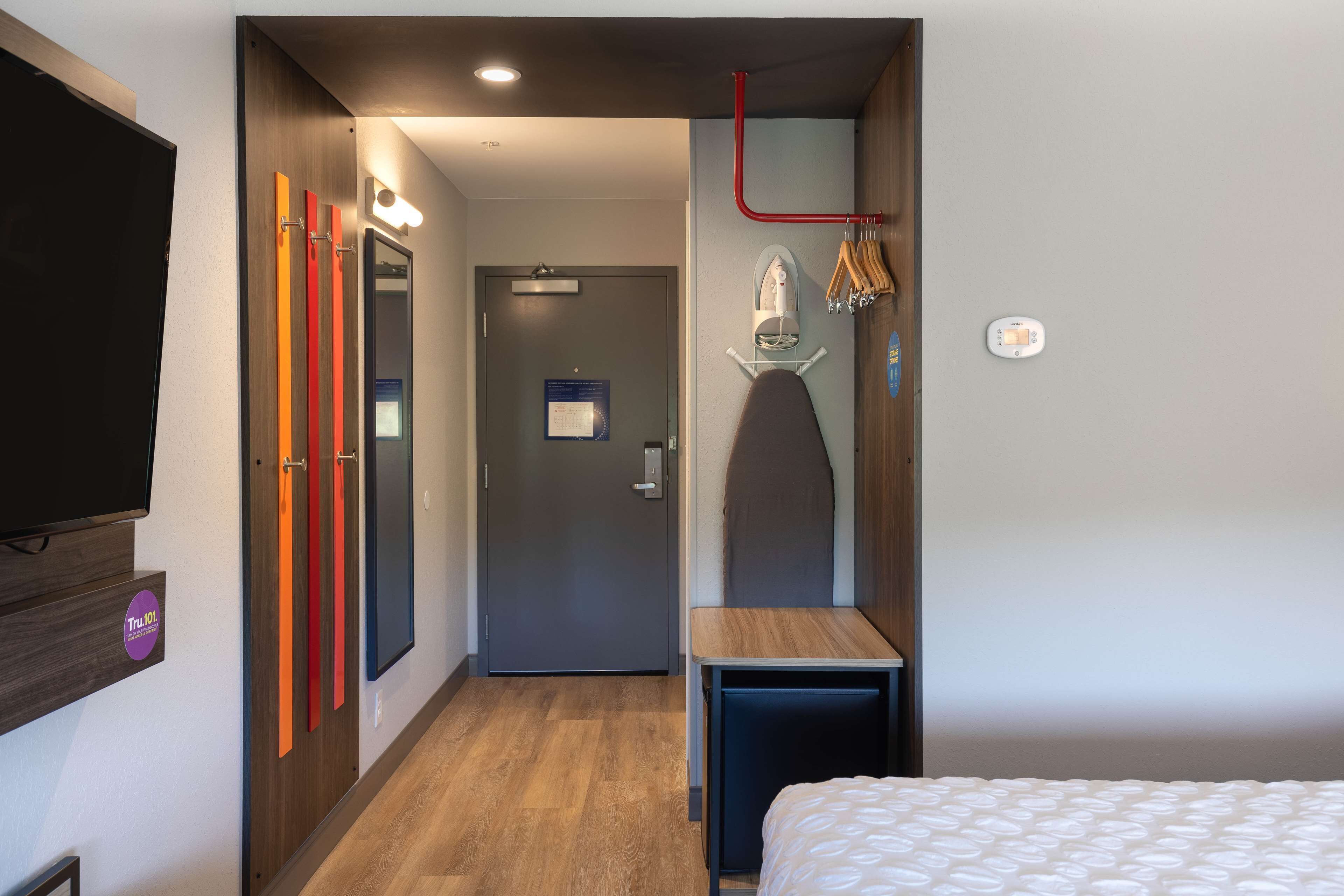 Une chambre d’hôtel avec un lit, une petite table, un miroir et un téléviseur fixé au mur.