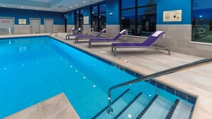 A swimming pool with lounge chairs and a safety sign.