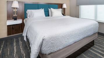 A hotel room with a large bed, two bedside tables with lamps, a headboard, and a window with a view.