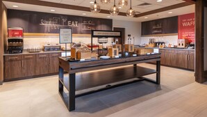 A modern breakfast area with a long counter, coffee machines, and a sign that reads "Happy Breakfast Starts Here".