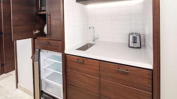 Una cocina compacta con refrigerador integrado, un lavamanos y un tostador.