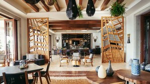 Amplia sala de estar con techo de madera, zona de bar y disposición de sofás y sillones.