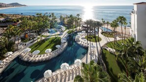 Un resort con una piscina grande, palmeras y vista al océano.