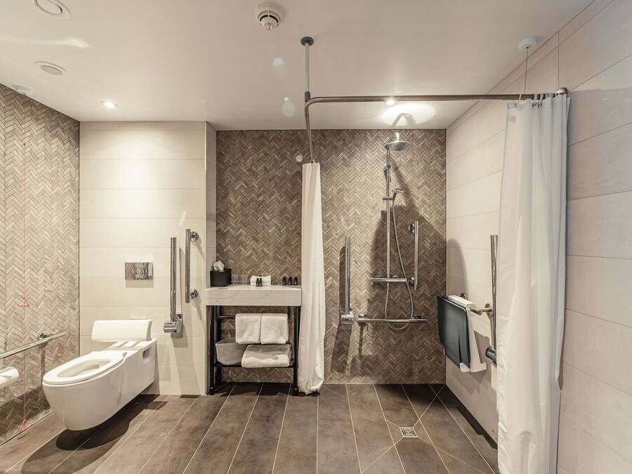 A modern bathroom with a toilet, sink, shower, and a towel rack.