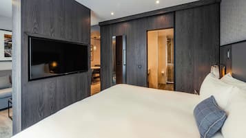 A modern bedroom with a large bed, a mounted TV, and dark wood paneling.