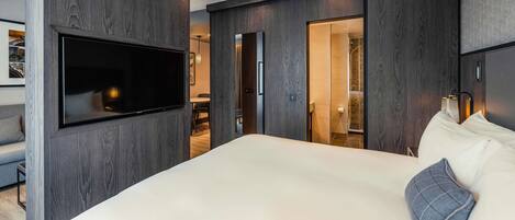 A modern bedroom with a large bed, a mounted TV, and dark wood paneling.