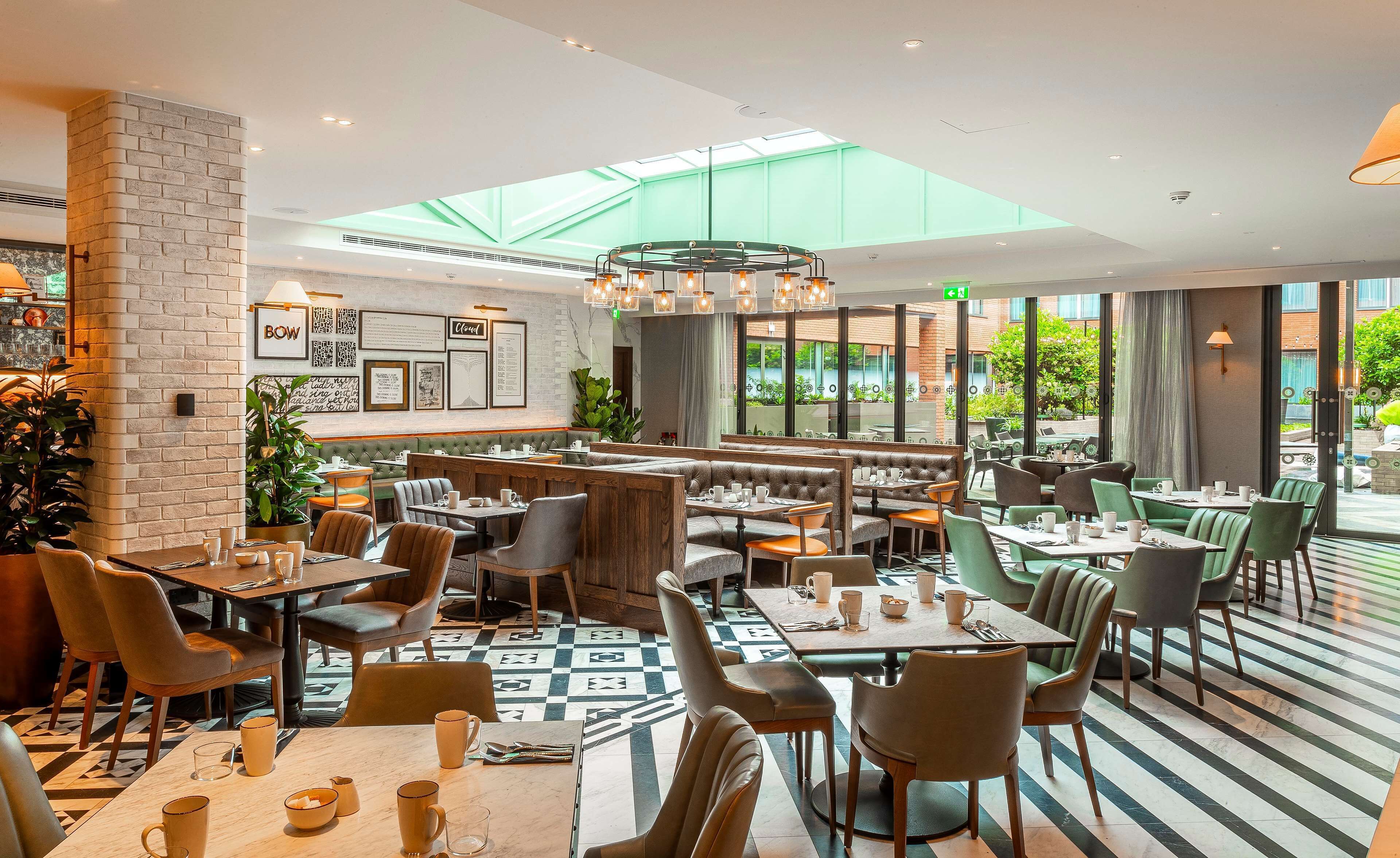 A modern restaurant with high ceilings, a skylight, and a mix of booth and table seating.