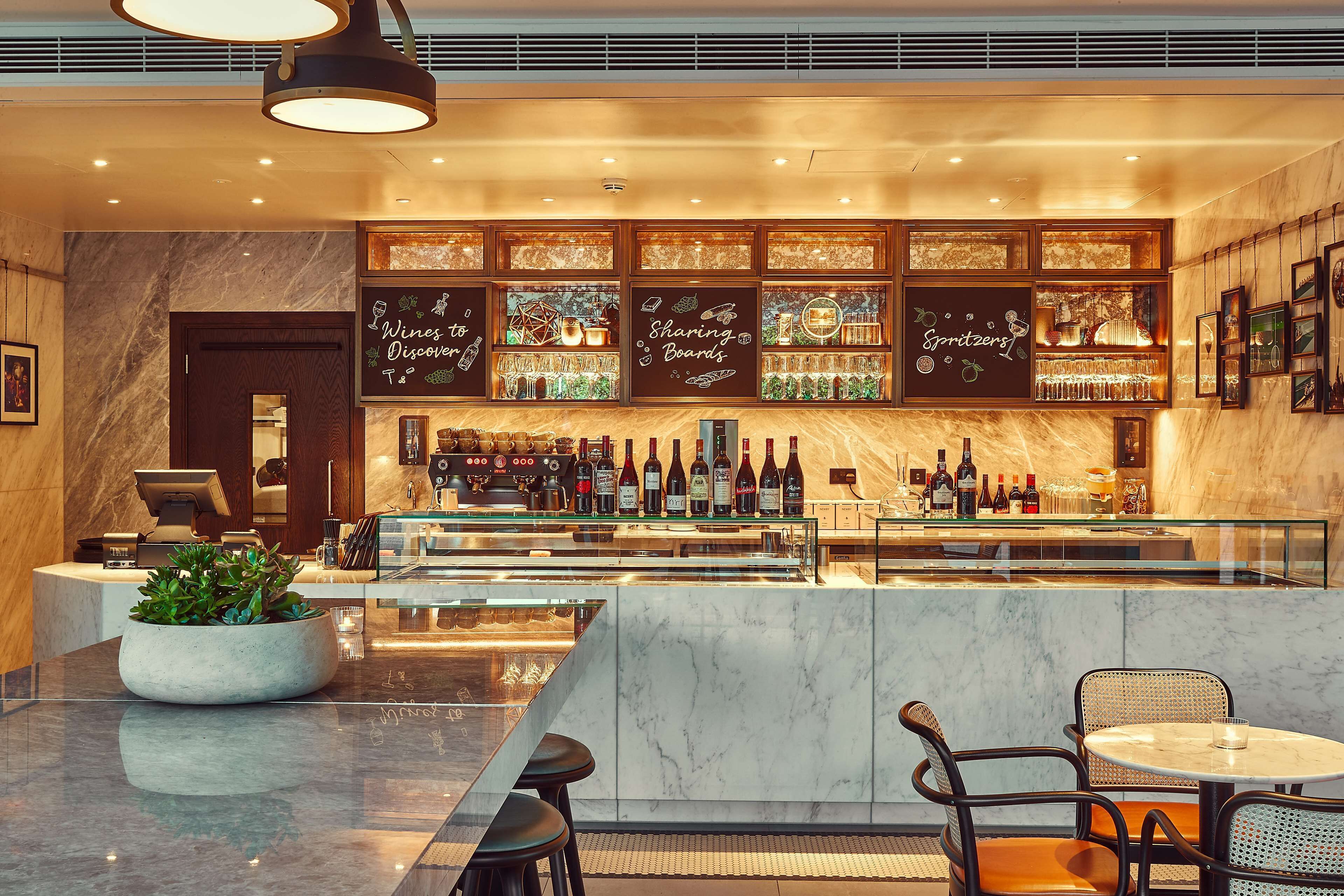 A bar area with a marble countertop, seating, and a variety of bottles and glasses.