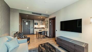 A modern living room with a sofa, a coffee table, a TV, and a dining area with chairs and a table.