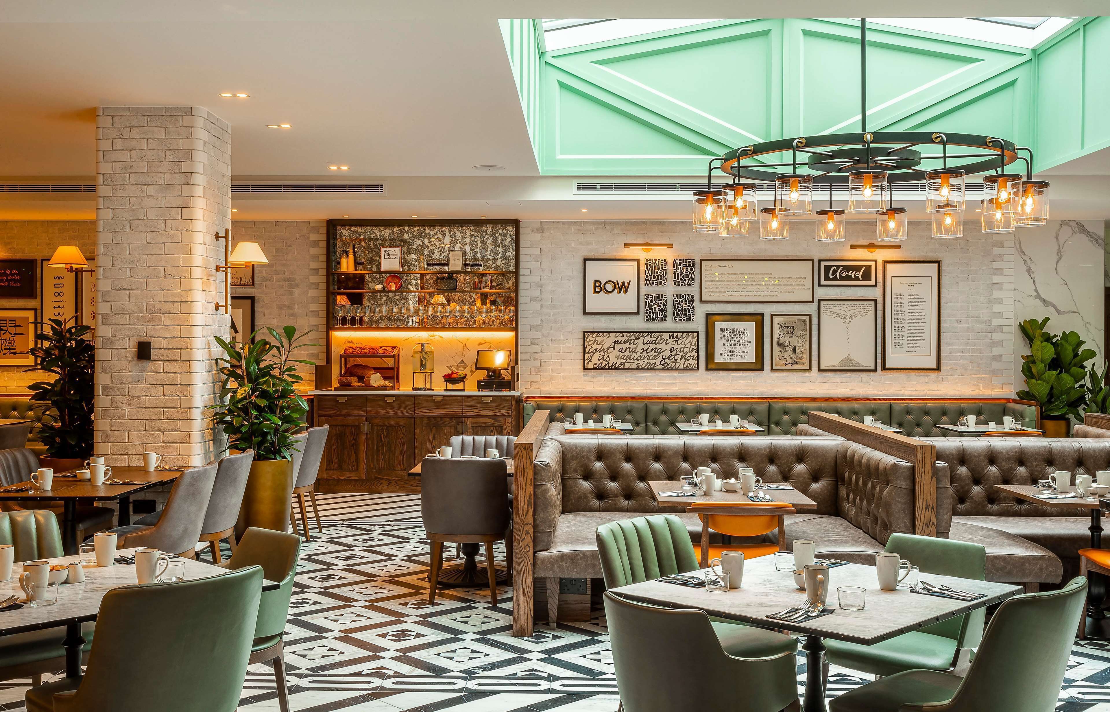A restaurant with a high ceiling, a bar area, and a seating arrangement including booths and tables.