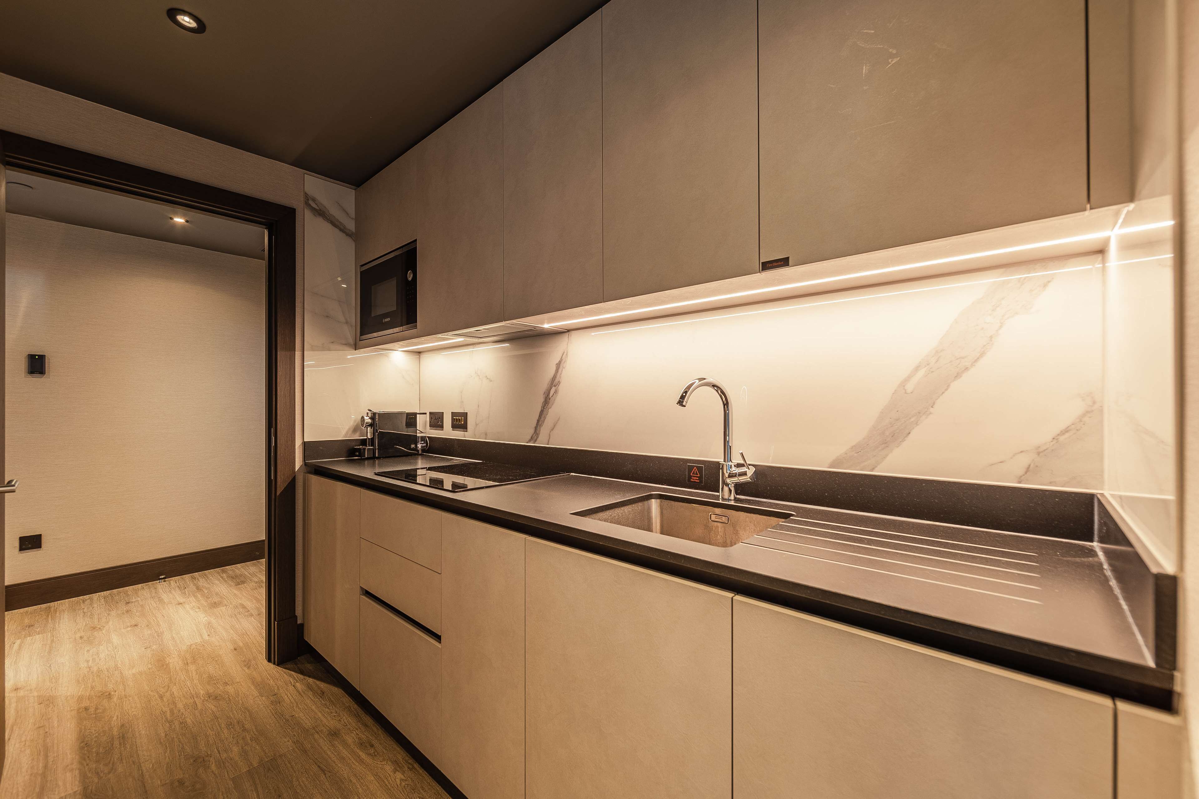 A modern kitchen with a marble countertop, stainless steel appliances, and a built-in microwave.