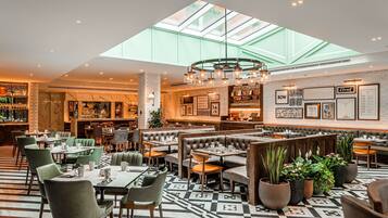 A spacious restaurant with high ceilings, a skylight, and a variety of seating options including booths and tables.