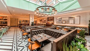 A modern restaurant with high ceilings, a central chandelier, and a mix of booth and table seating. - The Fellows House Cambridge, Curio Collection by Hilton (Cambridge)