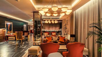 A spacious lobby with a modern chandelier, leather sofas, and a bar area.