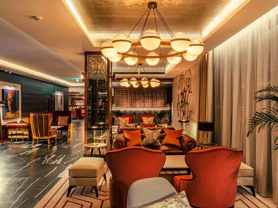 A spacious lobby with a modern chandelier, leather sofas, and a bar area.