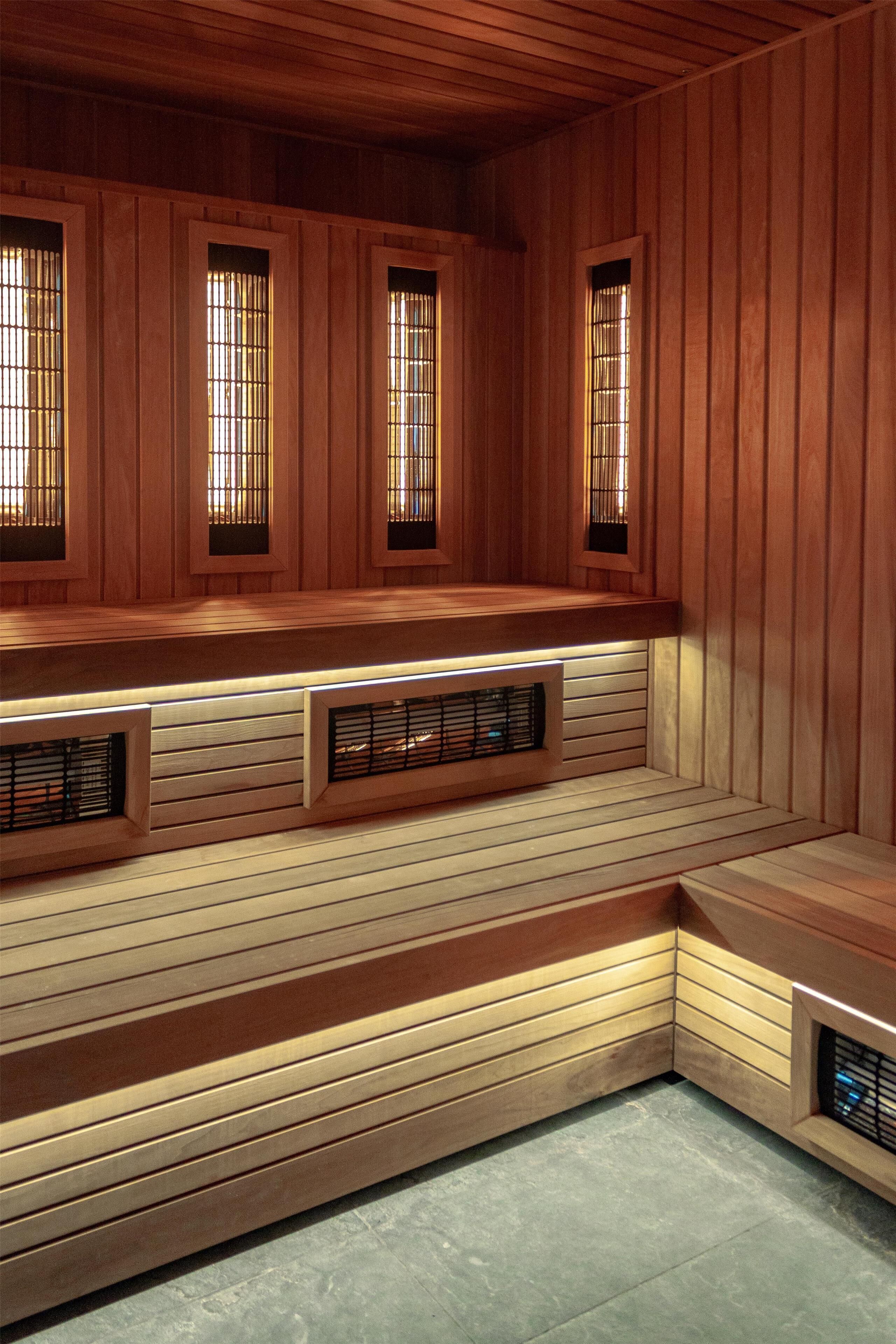 Uma sauna com paredes de madeira, um banco e três janelas com grades de metal.