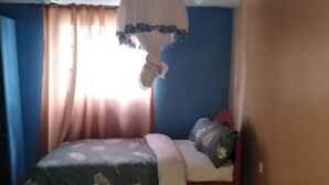 Une chambre à coucher avec un lit, des rideaux et un luminaire suspendu.