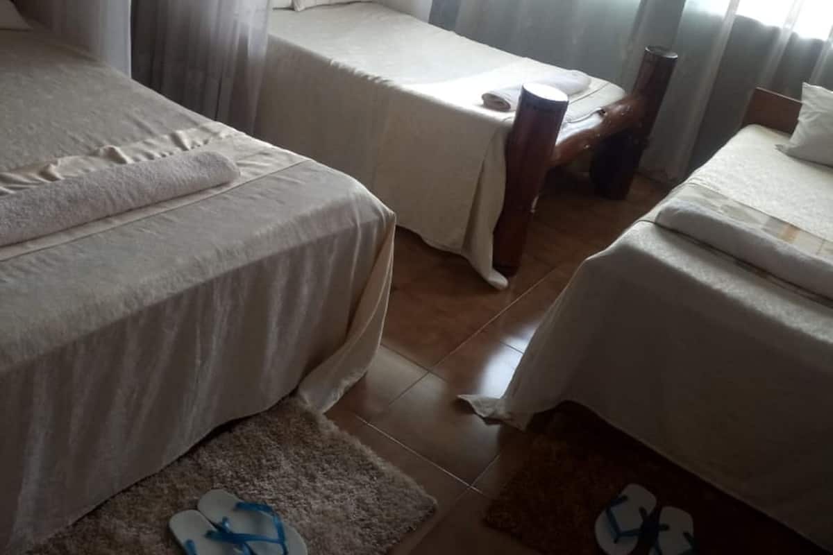 A hotel room with two beds, a wooden nightstand, and a window with sheer curtains.
