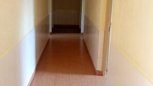 Un passadís estret amb terra de rajola i parets blanques.