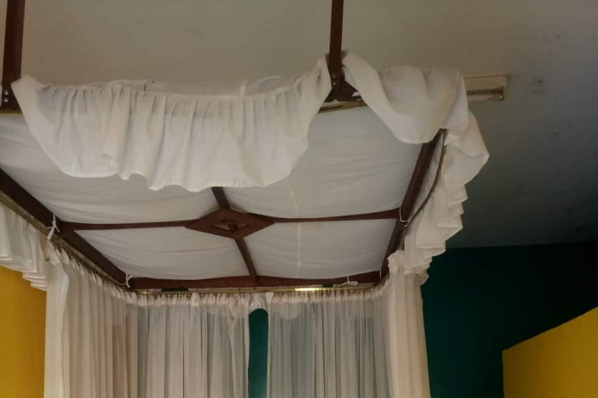 A bed with a canopy, white bedding, and a grey headboard.